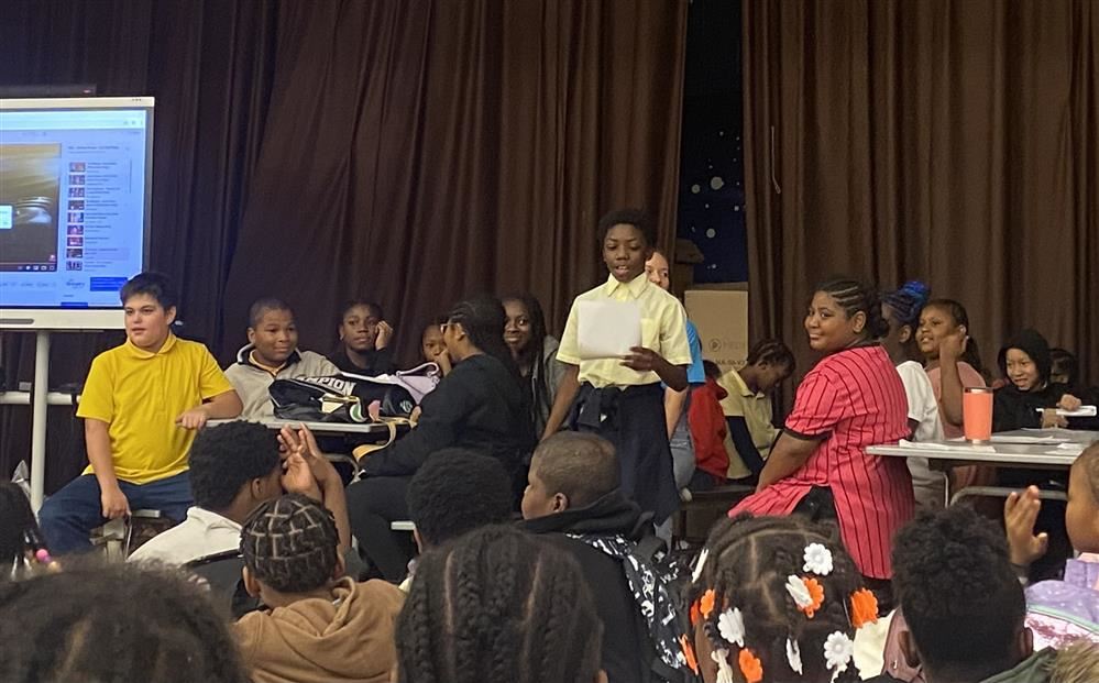 student reading from speech to a group of students