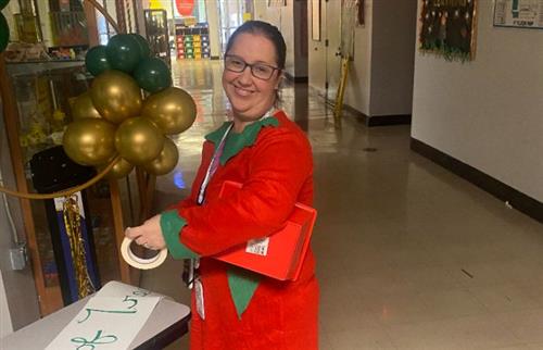 staff member dressed in elf clothing taping a sign