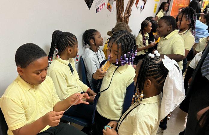 group of students in hallway standing around students sitting in chairs and reading their poems