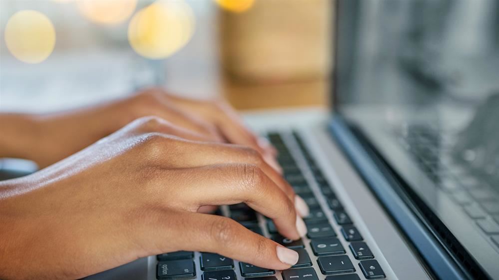  Fingers typing at a laptop keyboard.