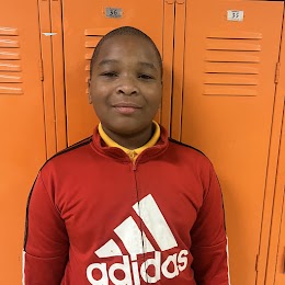 5th grade student smiling in front of orange lockers