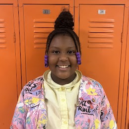 student smiling in front of lockers