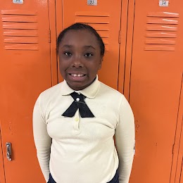 student in 4th grade standing in front of lockers smiling