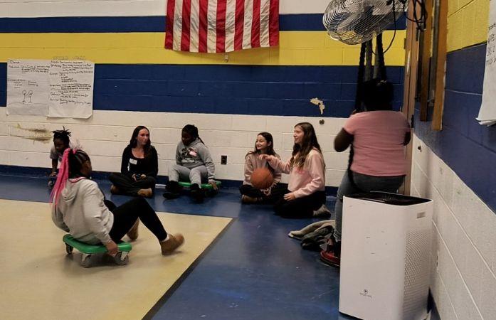 students sitting in a circle on scooters talking to high school students