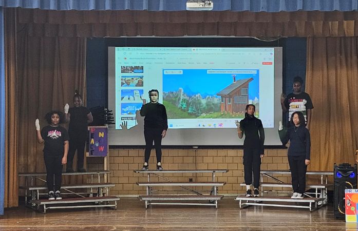  Six students standing on a stage with their right hand up.