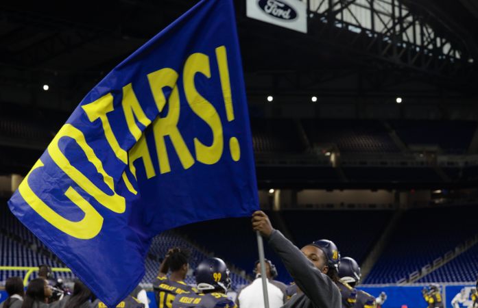  Student on the football field waving the Go Tars flag