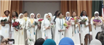  Students on stage in white gowns 