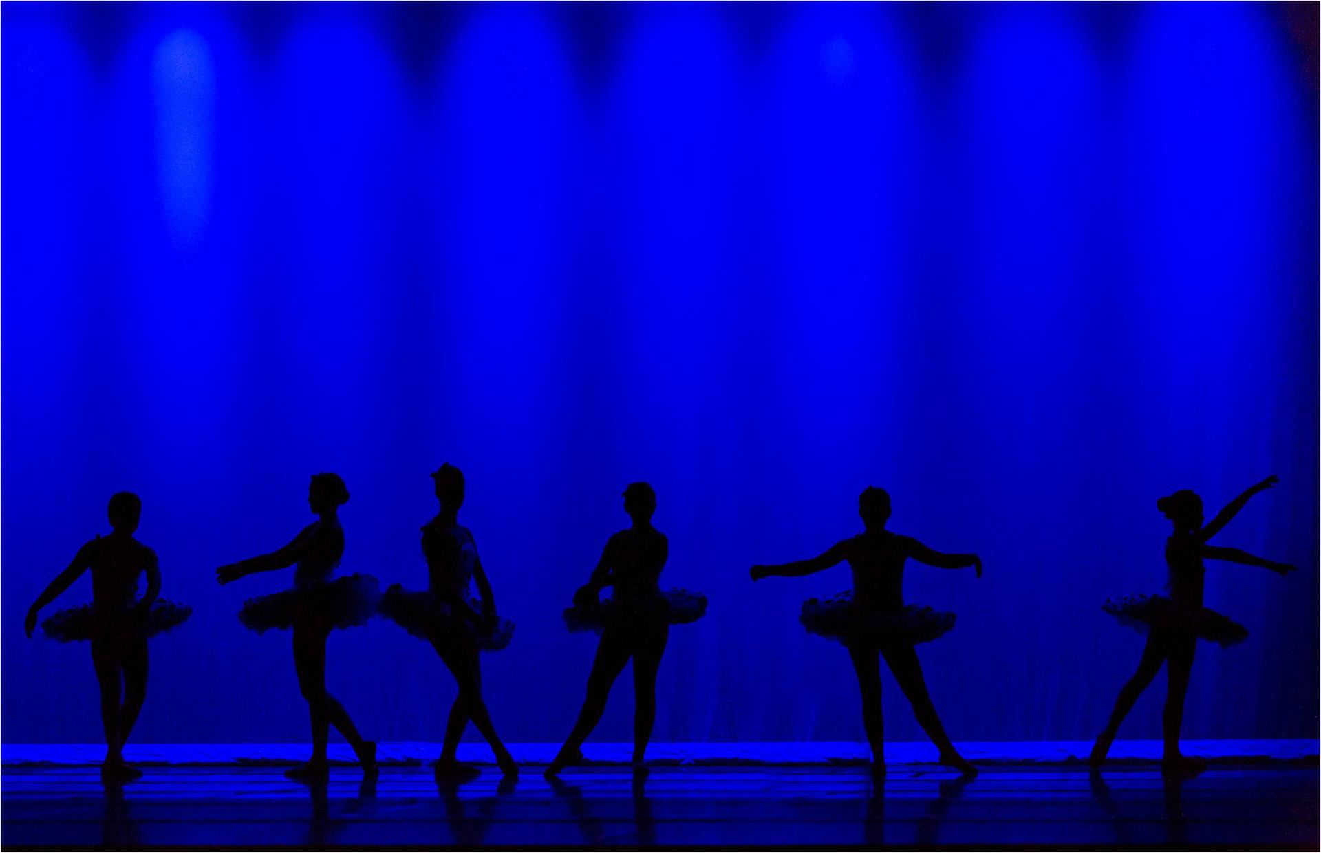  Dancers standing in blue light on a stage