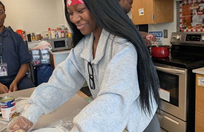 female student rolling dough for a pot pie