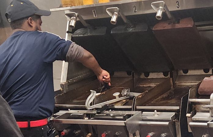 Male taking French fries out of grease