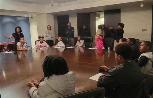 A female is talking to students sitting at a table