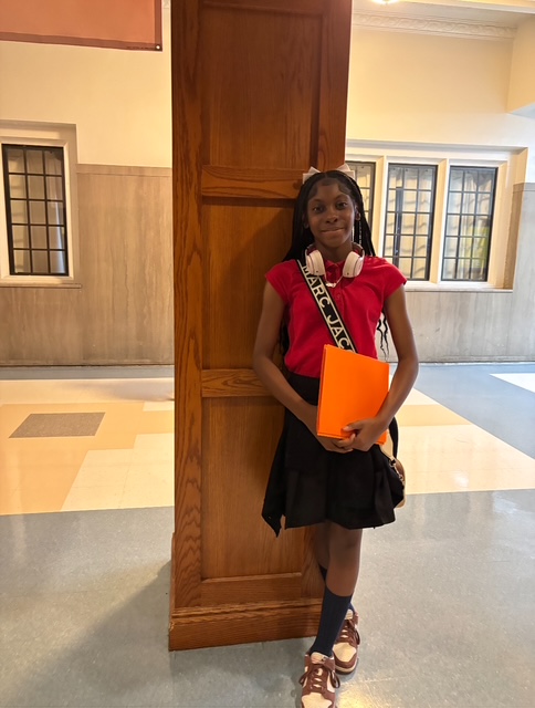 A girl standing with a red top and black bottoms