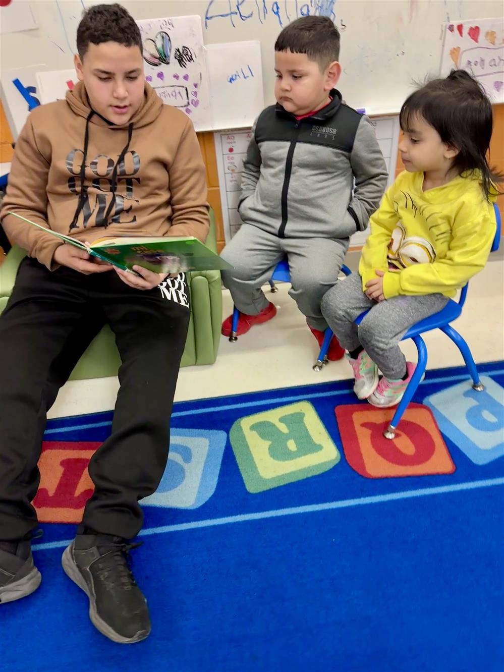  3 children with books reading together on a colorful carpet 