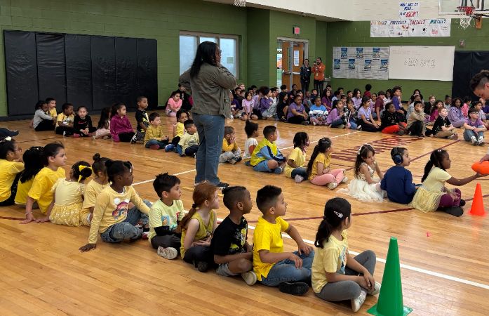  students sitting in rows in a gymnasium