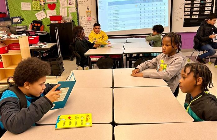  students sitting a desk reading