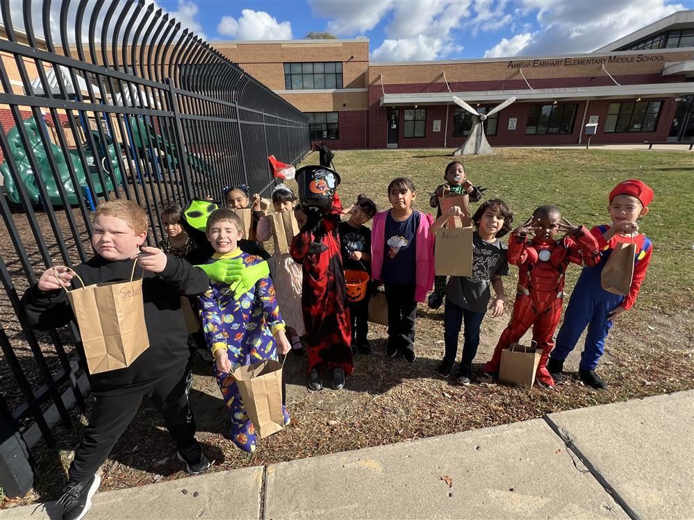 children in costumes holding candy bags smiling