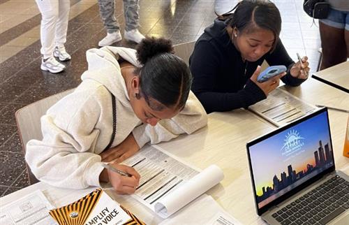  students sitting at lunch table filling out a voter registration application