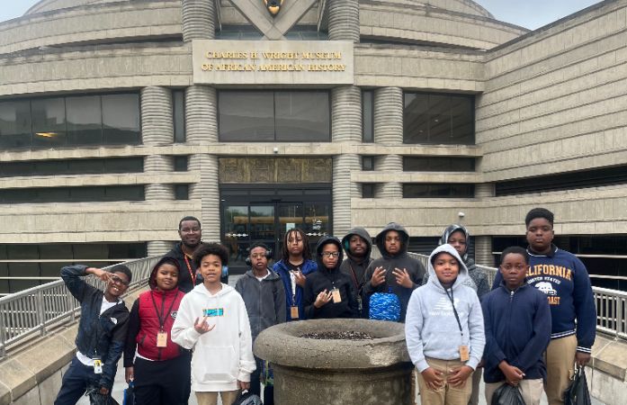  Students and teacher standing in front of the museum smiling for a picture