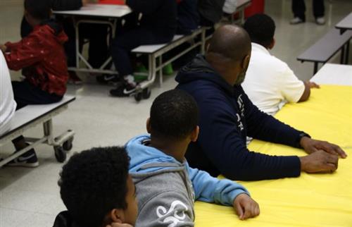 students sitting a lunch table with a dad