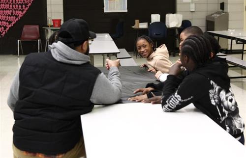 Students sitting at a lunch table talking with a dad
