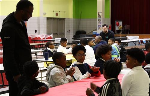 students sitting at a lunch table with a dad talking to them