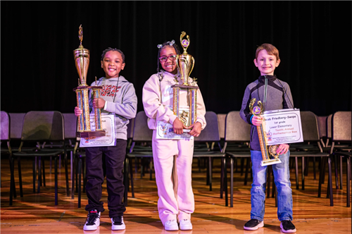 top 3 winners on stage holding trophies