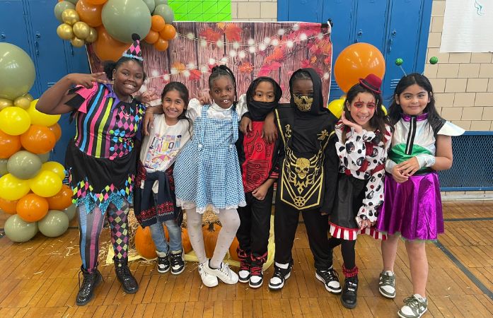  kids in costumes in front of props