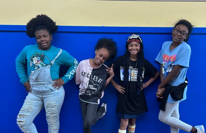  girls standing next to wall with anime shirts on