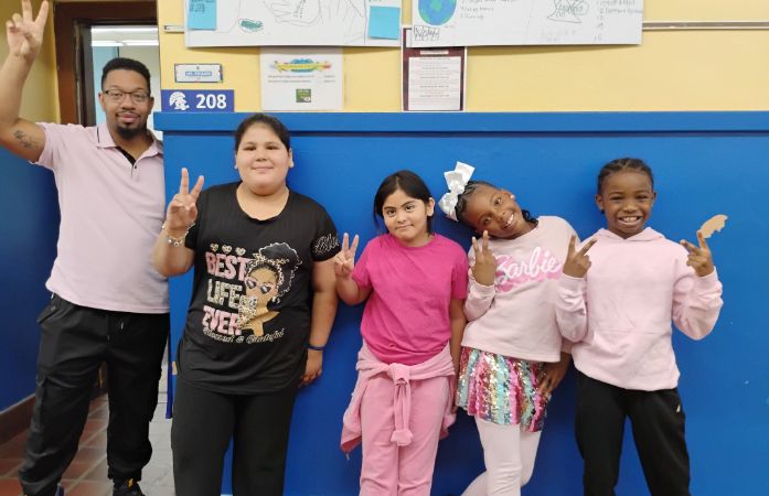  teacher and students wearing pink in hallway outside classroom