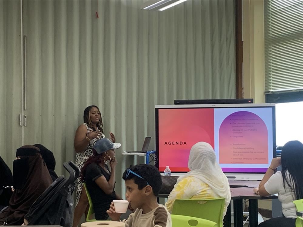  A group of people in a room with woman presenting on board