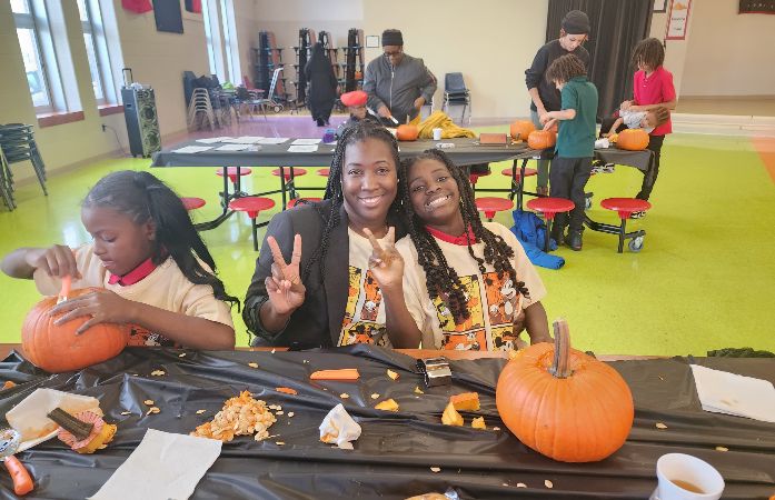  Mother and daughter smiling while carving a pumpkin