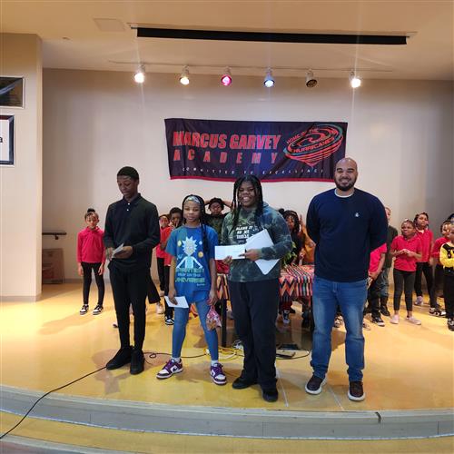Three students standing next to teacher on stage