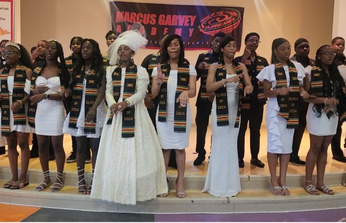  Female students dressed in white standing in front of male students dressed in black