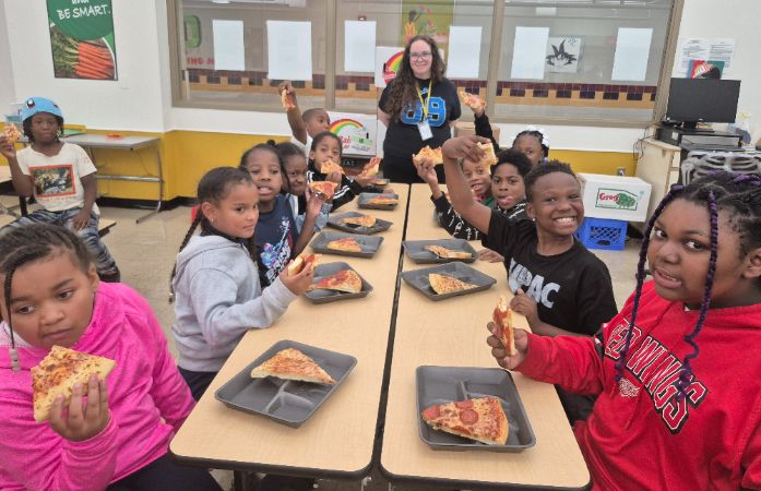  Students and teacher are eating pizza at lunch room