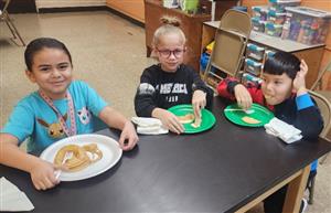 2nd graders, 2 girls and 1 boy eating pancakes