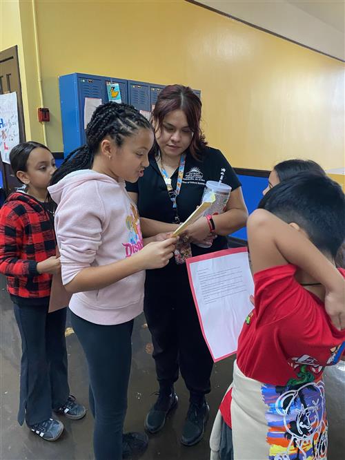 5th grade students proudly reading their work to Ms. Jocelyn