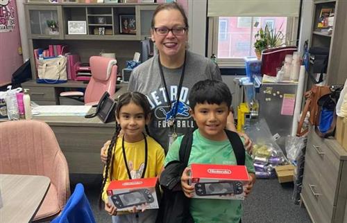  Principal Ramos standing with the two winners of a Nintendo Switch