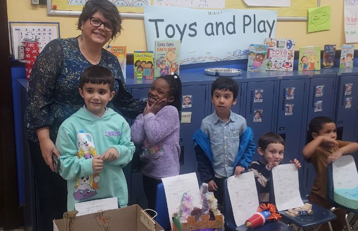  Kindergarten teacher and students proudly showing their work 