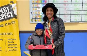 Pizza winner and Attendance Agent smiling while student hold his pizza to take home