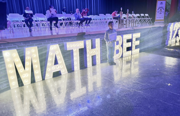  Student standing by a sign smiling