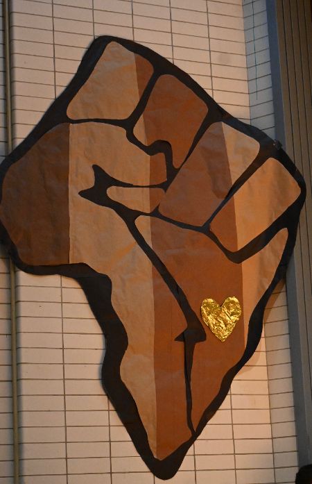 a brown paper raised fist shaped like the African continent, symbolizing strength and unity. 