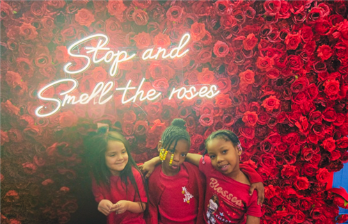 students hugging in front of Stop and Smell the roses sign