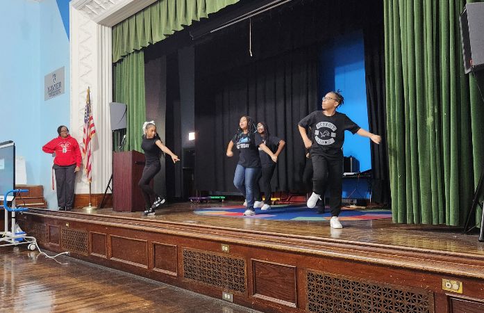  students on auditorium stage cheering